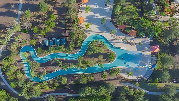 Vue aérienne d’un complexe hôtelier doté d’un toboggan aquatique sinueux, entouré de verdure et de sentiers.