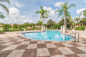 A swimming pool with a checkered tile deck, surrounded by palm trees and a clear sky. - Cozy Villa 3bd/3ba - King Bed - Private Jacuzzi (Kissimmee)