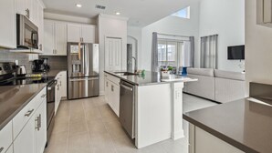 Una cocina moderna con electrodomésticos de acero inoxidable, armarios blancos y una isla grande.