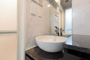 A bathroom with a large white vessel sink, dark marble countertop, and a mirror reflecting the room. - LaVie Hatsudai (Tokyo)