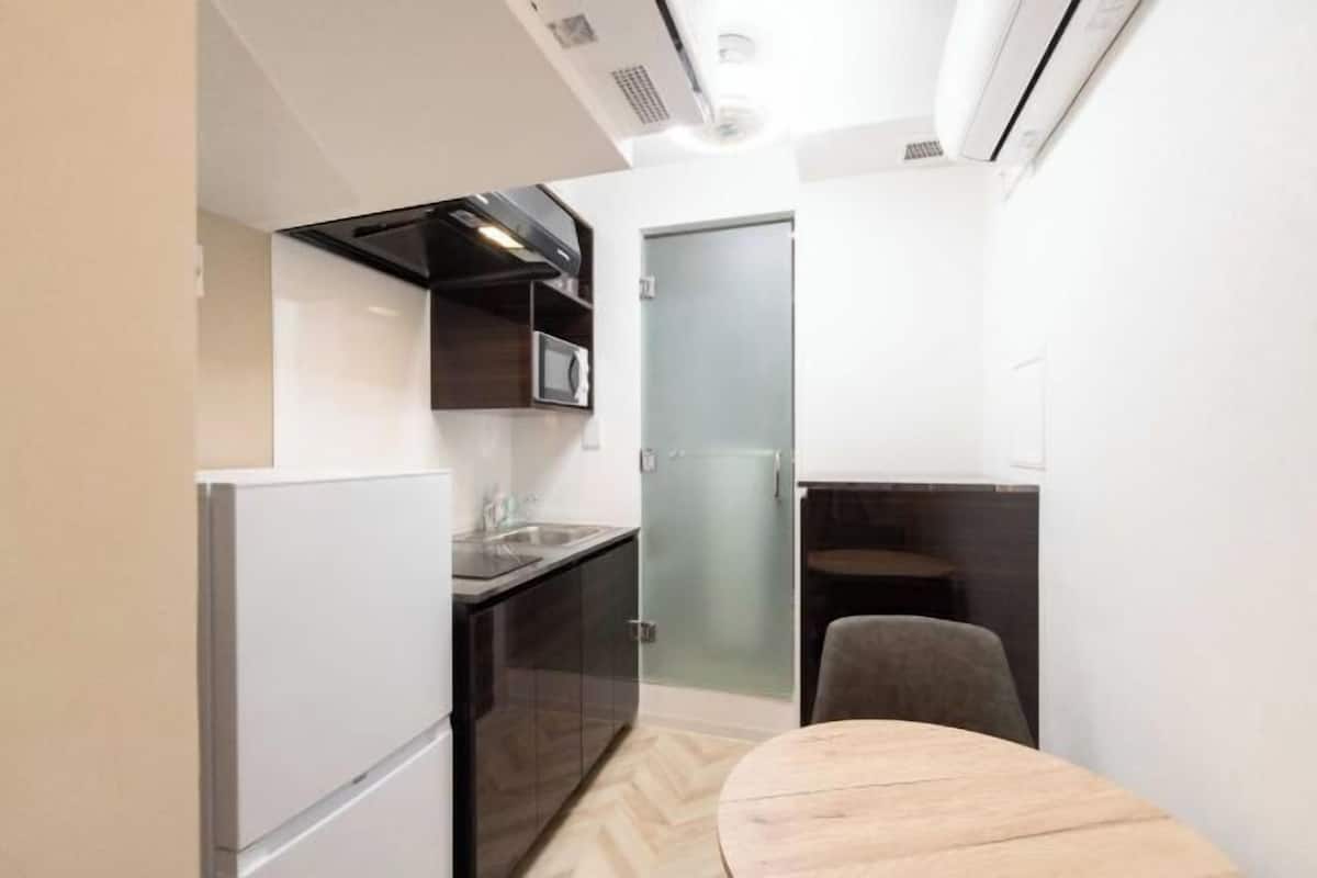 A compact kitchen with a microwave, refrigerator, and a small dining area with a table and chair.