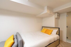 Ein Schlafzimmer mit Bett, Nachttisch, Wandklimaanlage und Tür.