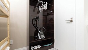 A room with a built-in vacuum cleaner, a shoe rack, and a door with a handle. - LaVie Hatsudai (Tokyo)