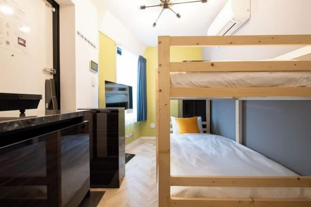 A bunk bed room with a desk and a TV.