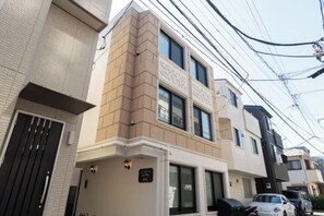 A residential building with a flat facade, large windows, and a visible garage door. - LaVie Hatsudai (Tokyo)