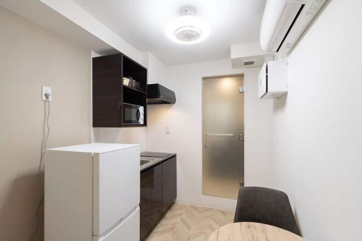A compact kitchen with a refrigerator, microwave, and dark cabinetry.