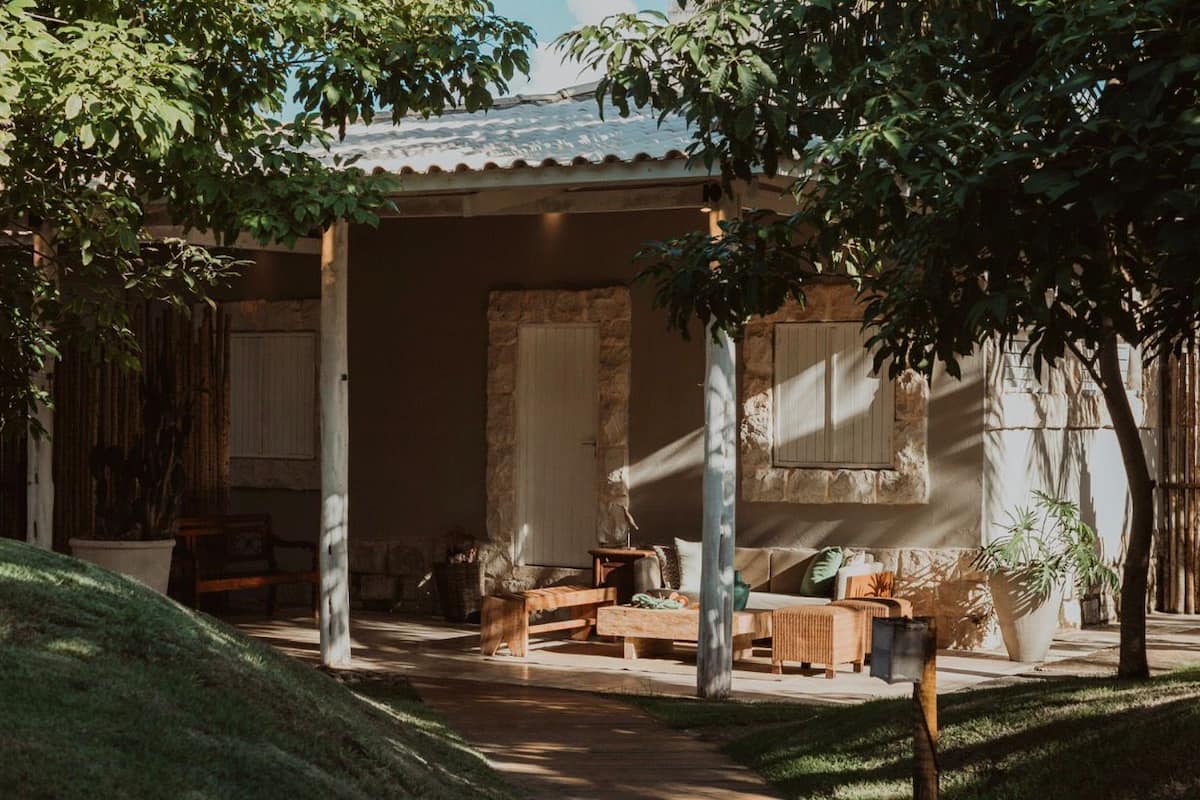 Un espace extérieur aménagé, abrité et doté de mobilier en bois, de murs en pierre et de plantes en pot.