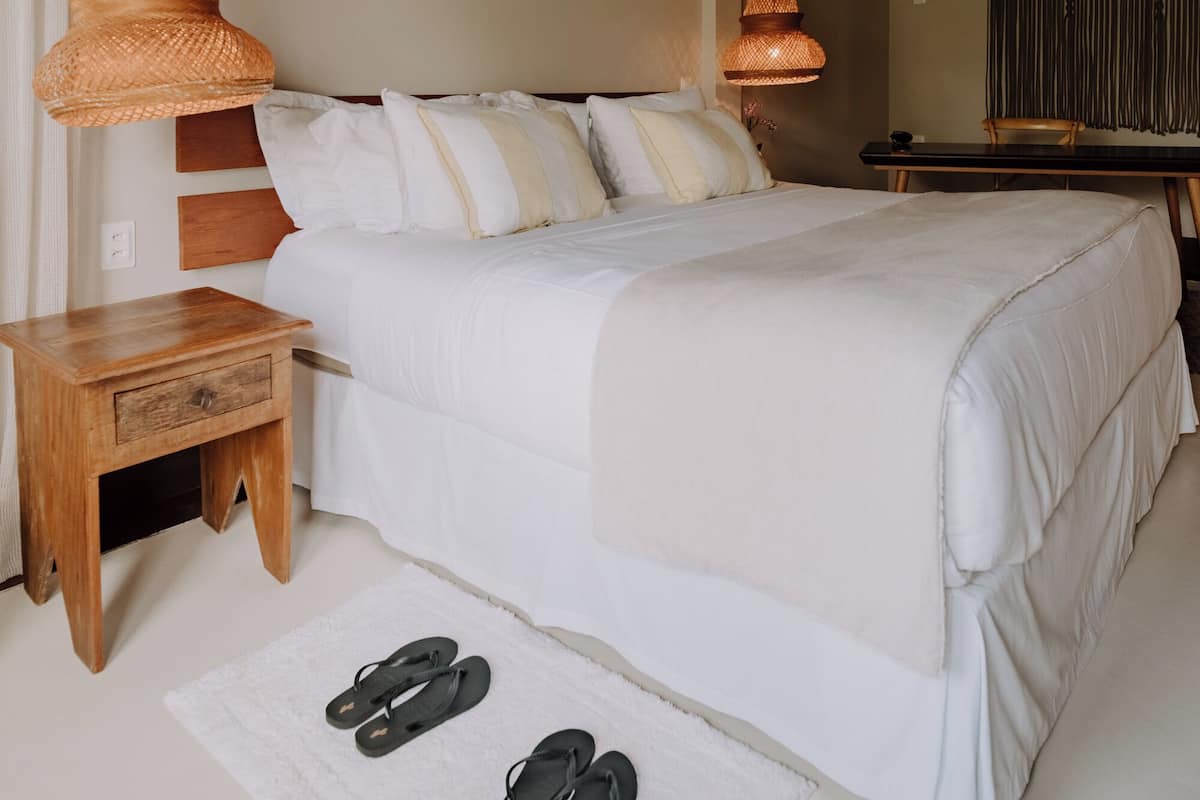 Une chambre à coucher avec un grand lit, une table de chevet en bois et une lampe suspendue.