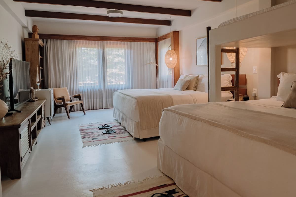 Une chambre d’hôtel avec deux lits, un bureau avec une télévision, une chaise et un tapis à motifs.