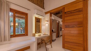 A room with a wooden door, a desk with a chair, a window with curtains, and an air conditioning unit.