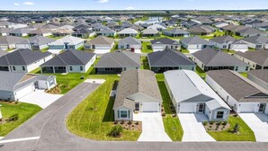 A residential area with multiple two-story houses, each with a garage, driveway, and small front yard. - Spacious 2BR in The Villages | GolfCart | King Bed (Sumterville)