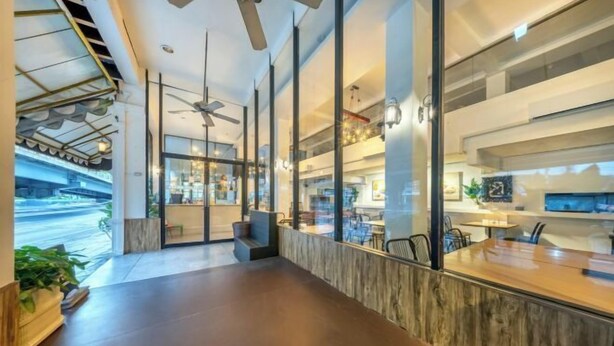 A modern interior with a long reception desk, glass partitions, and ceiling fans. - SHIN Hotel Victory Monument (Bangkok)
