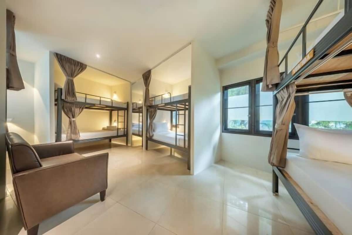 A modern hotel room with bunk beds, a sofa, and large windows.