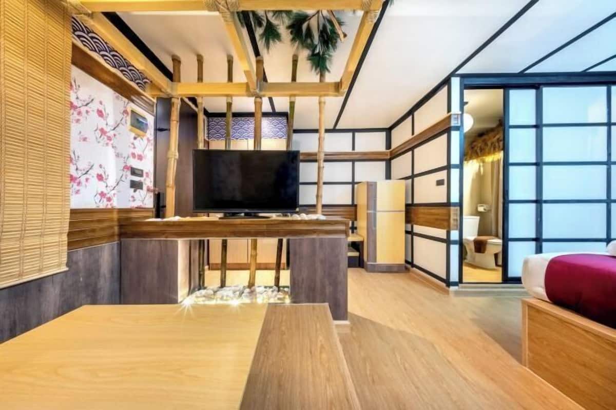 A modern interior with a wooden dining table, a flat-screen TV, and a traditional Japanese-style room with sliding doors and tatami mats.