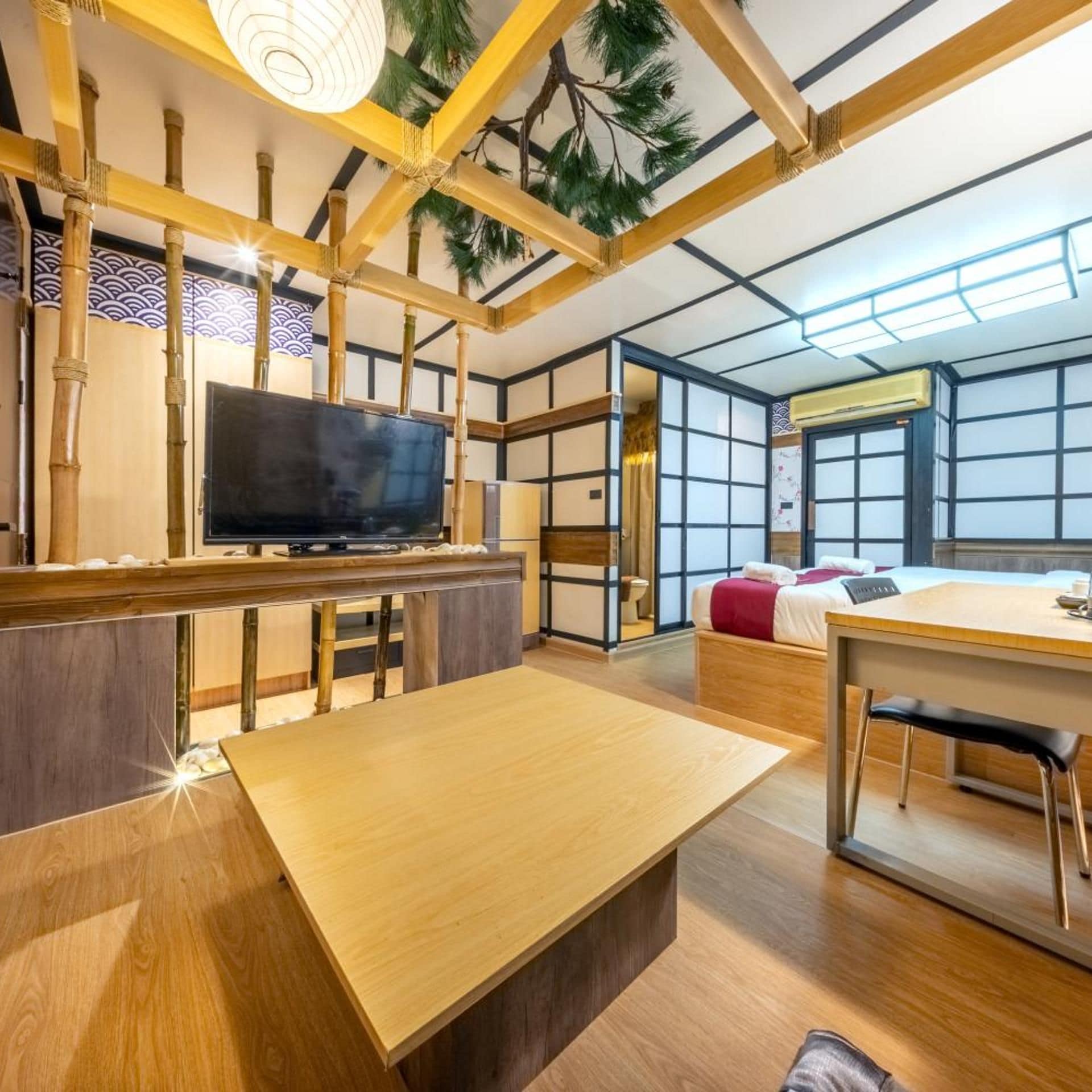 A traditional Japanese-style room with tatami flooring, a television, a bed, and a dining area.