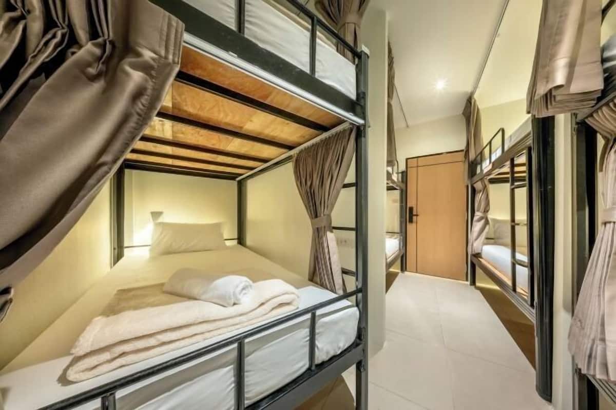 A bunk bed room with curtains, a bedside lamp, and a wooden ceiling.