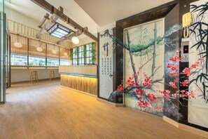 A restaurant with a wooden interior, a counter, and a mural of bamboo and flowers. - SHIN Hotel Victory Monument (Bangkok)