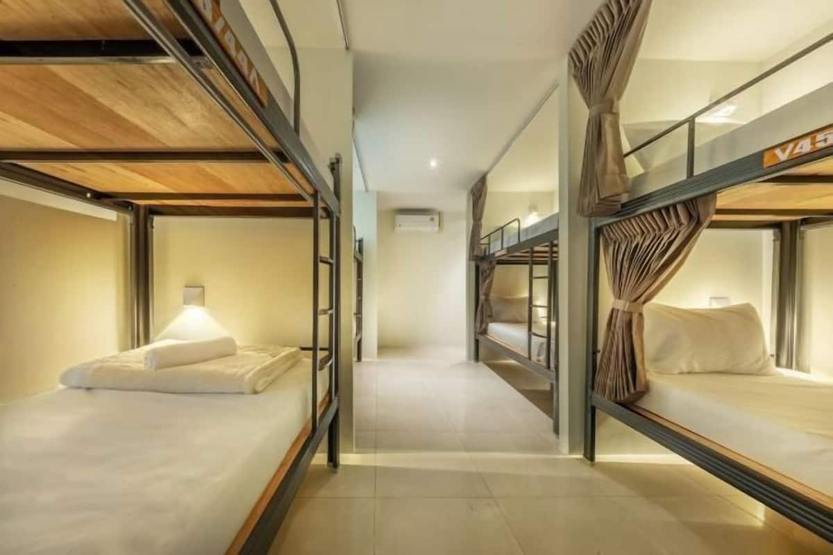 A corridor with bunk beds, a wall-mounted air conditioner, and a visible room number sign.