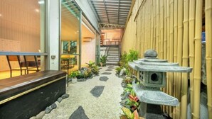 A narrow corridor with a stone path, bamboo wall, and a stone lantern. - SHIN Hotel Victory Monument (Bangkok)
