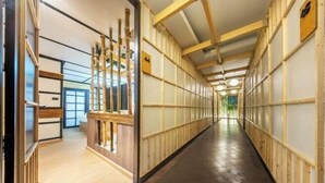 A hallway with wooden paneling, a reception desk, and a view into another room. - SHIN Hotel Victory Monument (Bangkok)
