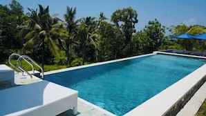 A rectangular swimming pool with clear blue water, surrounded by lush greenery and palm trees. - d’Kelingking Secret Villas (Bali)