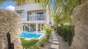 A modern two-story house with a swimming pool, surrounded by palm trees and a stone pathway. - Aqua - Brand New Luxury Beach House on AMI (Bradenton Beach)