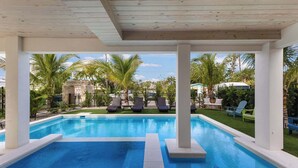 A pool area with lounge chairs and palm trees. - Aqua - Brand New Luxury Beach House on AMI (Bradenton Beach)