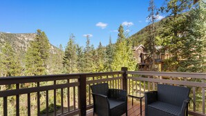 A wooden deck with two wicker chairs and a small table, overlooking a mountainous landscape. - Settlers Creek #6559 (Keystone)