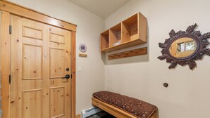 A hallway with a wooden door, a small bench, a mirror, and a clock on the wall. - Settlers Creek #6559 (Keystone)