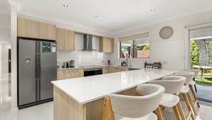 Une cuisine moderne dotée d’un grand îlot central, d’appareils électroménagers en acier inoxydable et de meubles de rangement en bois.
