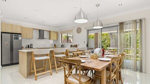 Une cuisine moderne dotée d’un îlot central, de chaises en bois et d’une table à manger pouvant accueillir six personnes.