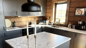 A modern kitchen with marble countertops, black cabinets, and a large window providing natural light. - Mountain cabin for the whole family - near skiing, golf and hiking | SE19053 (Idre)