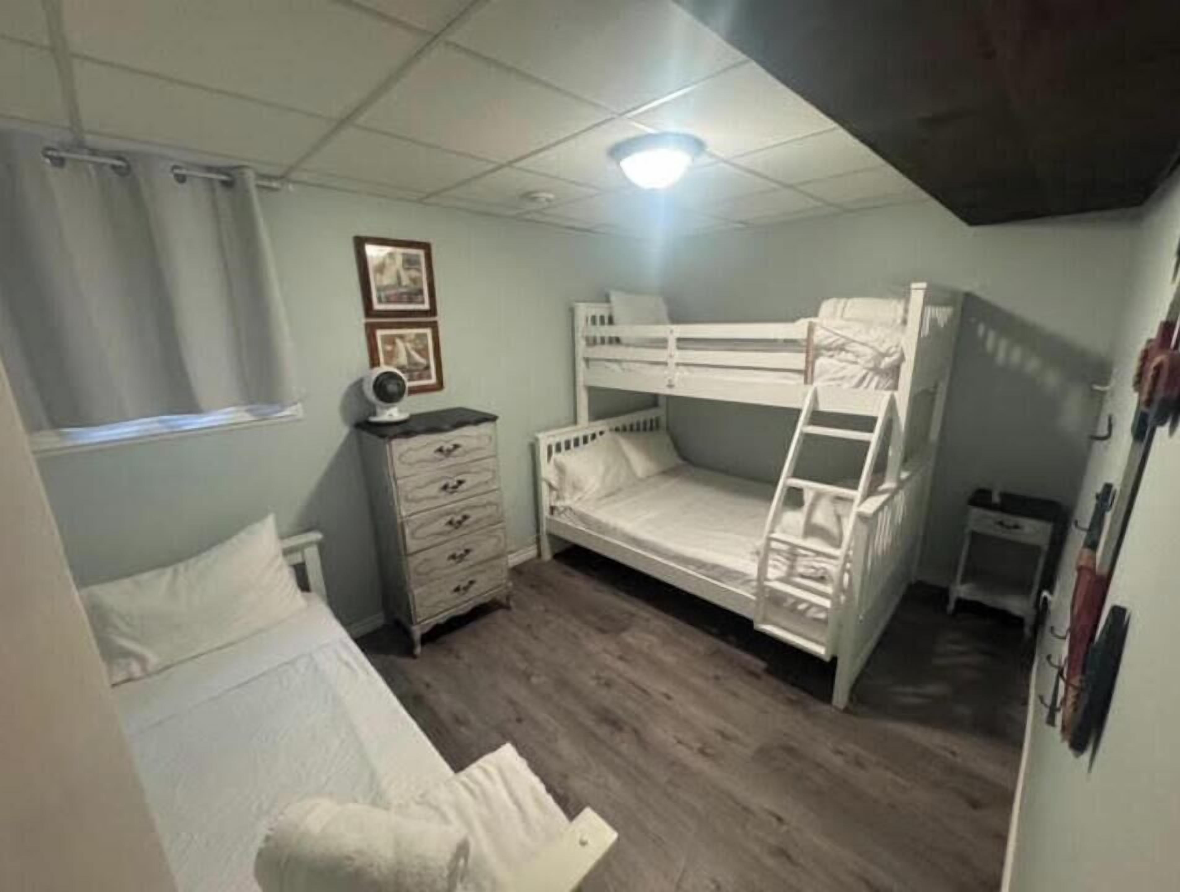 Habitación con literas, cómoda y ventana con cortinas.
