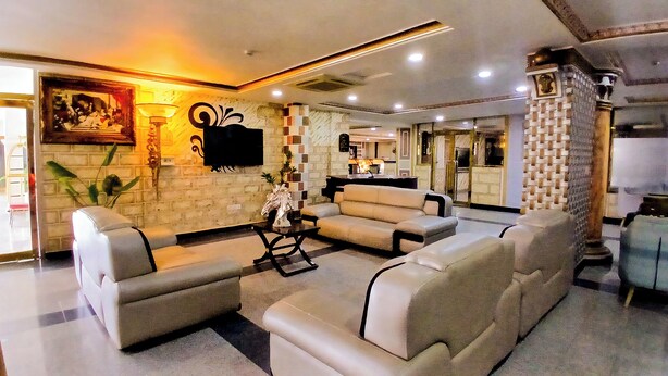 A modern living room with a sofa set, a flat-screen TV, and a decorative wall piece. - AAHotel Abuja (Abuja)