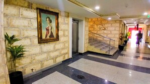 A hallway with tiled walls, a staircase, and potted plants. - AAHotel Abuja (Abuja)