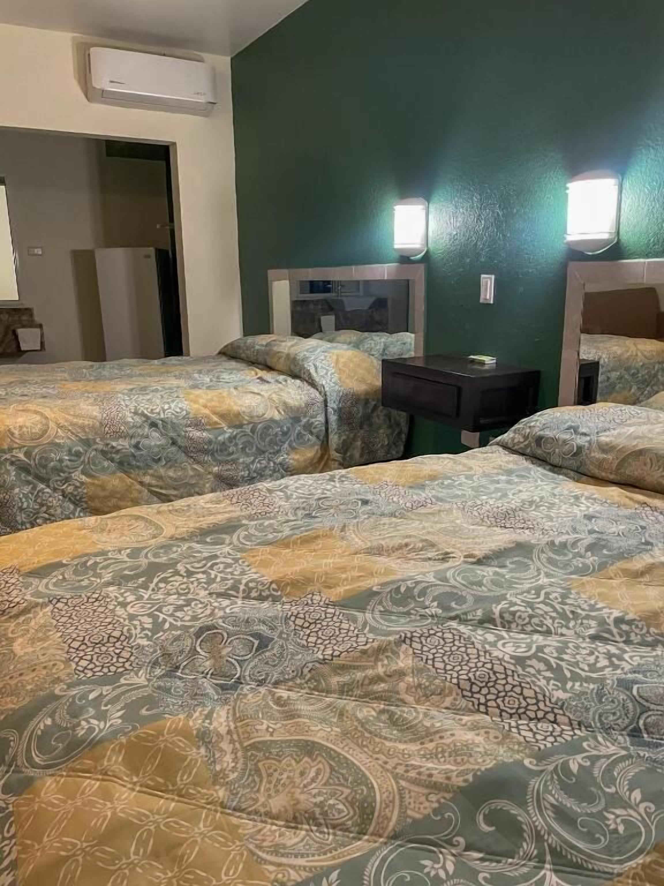 A hotel room with two beds, a desk, and a mirror.