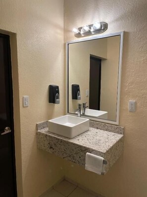 A bathroom with a white sink, a large mirror, and a soap dispenser. - Motel Apolo 69 (Santa Ana)