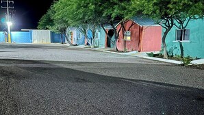 Une rangée de petites cabanes colorées, avec des arbres devant, sous un ciel nocturne.
