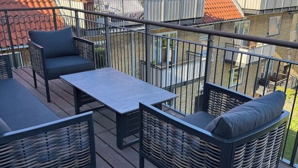 En balkon med fletmøbler, et bord og gelænder.