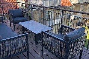 Un balcon doté de meubles en osier, d’une table et d’une rambarde.