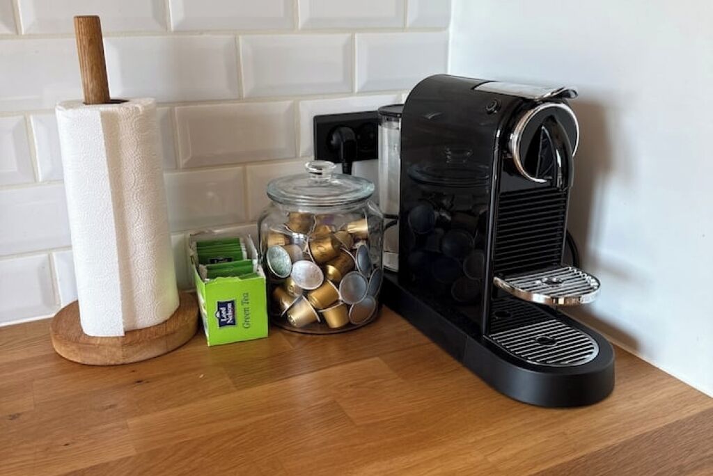 A kitchen area with a coffee maker, a paper towel holder, and a jar of coins.