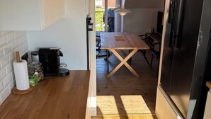 Et køkken med et træbord, et sort køleskab og en kaffemaskine.