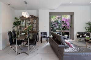 A modern living room with a dining area, a sofa, and a glass table.