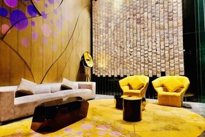A modern interior with a sofa, yellow armchairs, and a patterned rug. - Queen Suites Tropicana The Residence by KLCC (Kuala Lumpur)