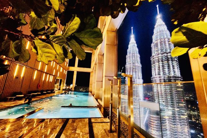 Zona de piscina con vista a las Torres Petronas iluminadas de noche.