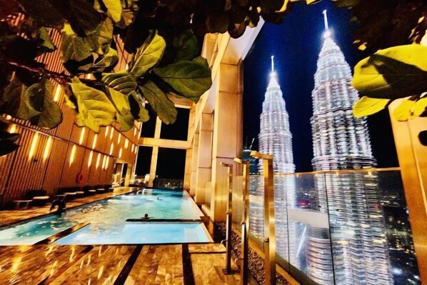 A pool area with a view of the Petronas Twin Towers at night. - Queen Suites Tropicana The Residence by KLCC (Kuala Lumpur)