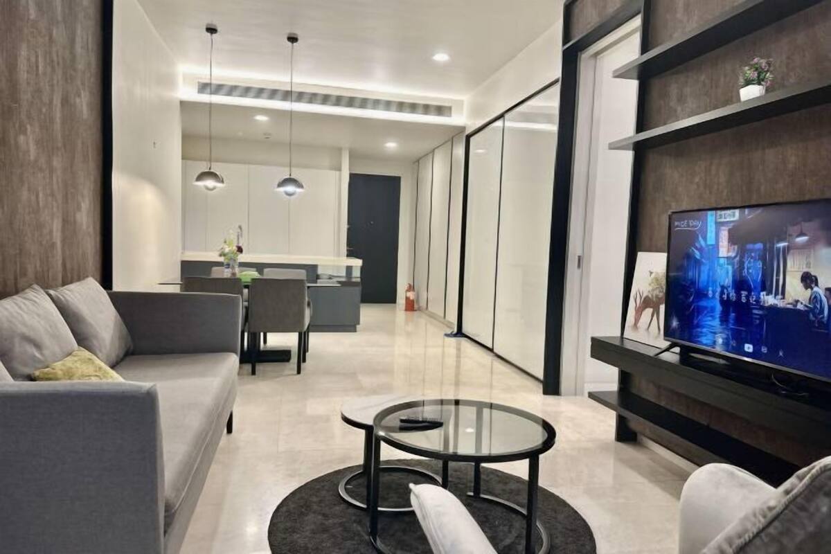 A modern living room with a sofa, a glass coffee table, and a flat-screen TV.