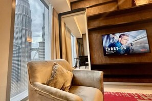 A modern living room with a large window, a comfortable sofa, a flat-screen TV, and a view of a tall building. - Queen Suites Tropicana The Residence by KLCC (Kuala Lumpur)