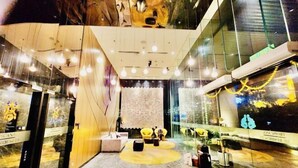 Un hall d’entrée moderne avec un sol en marbre, des espaces de détente et un mur en verre orné d’une fresque décorative.