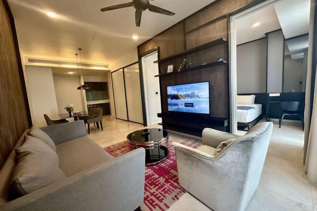 A modern living room with a sofa, armchairs, a TV, and a dining area.